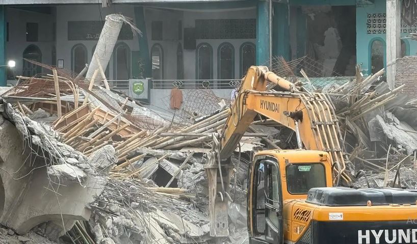 Rencana Pemerintah Bangun Ulang Ponpes Al Khoziny Dinilai Bisa Merusak TKP Alat berat telah dikerahkan untuk membantu proses evakuasi material puing bangunan insiden ambruknya musala Pondok Pesantren (Ponpes) Al Khoziny, Sidoarjo, Jawa Timur, Minggu (5/10/2025). (Foto: BNPB)