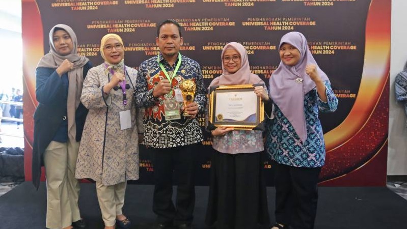 Pj walikota Tangerang Nurdin memperlihatkan piala dan piagam penghargaan UHC Award 2024. [Foto: Dok Pemkot]