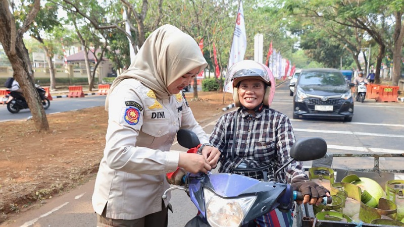 Petugas Satpol PP Kabupaten Tangerang sedang memasangkan bendera ke pengendara motor - Foto: Dok. Diskominfo Tangerang -