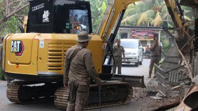 Alat berat dan Satpol PP menertibkan bangunan yang berdiri di atas dinase, di Cikupa, Kabupaten Tangerang. [Foto" DOk Pemkab]